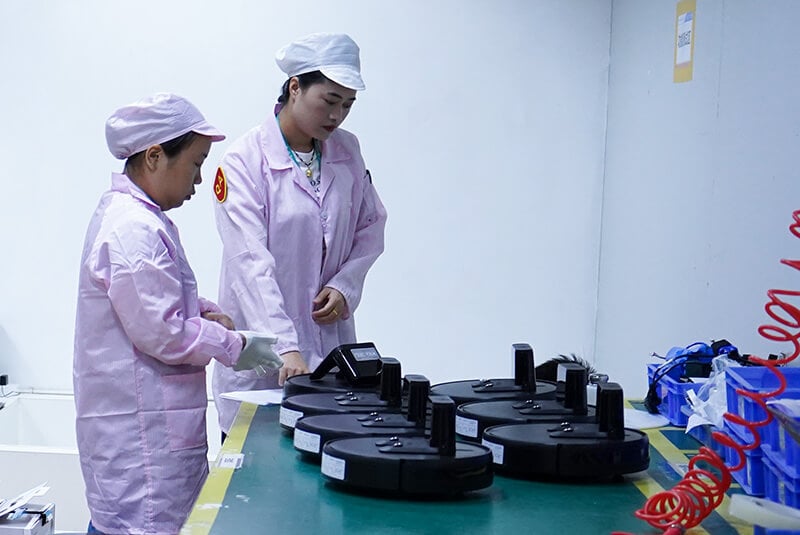 Minfu workers in anti-static uniforms performing strict quality control and inspection on robot vacuums